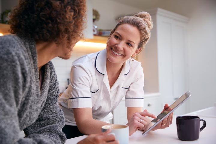 Care consulting image - nurse smiling at consultant holding iPad